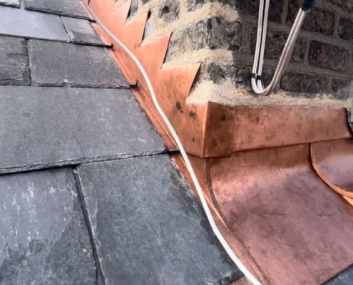 Copper flashing around a chimney on a slate roof