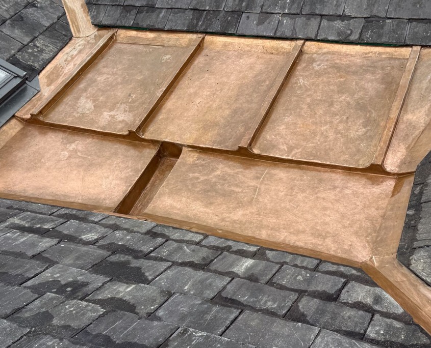 Copper roofing panels laid over a slate roof